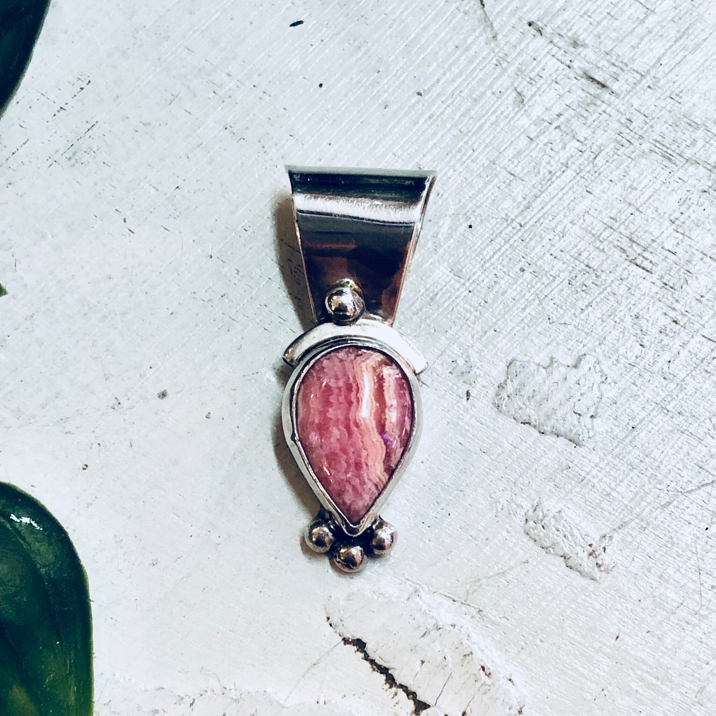 Vintage sterling silver pendant with pink rhodochrosite gemstone on a white textured background