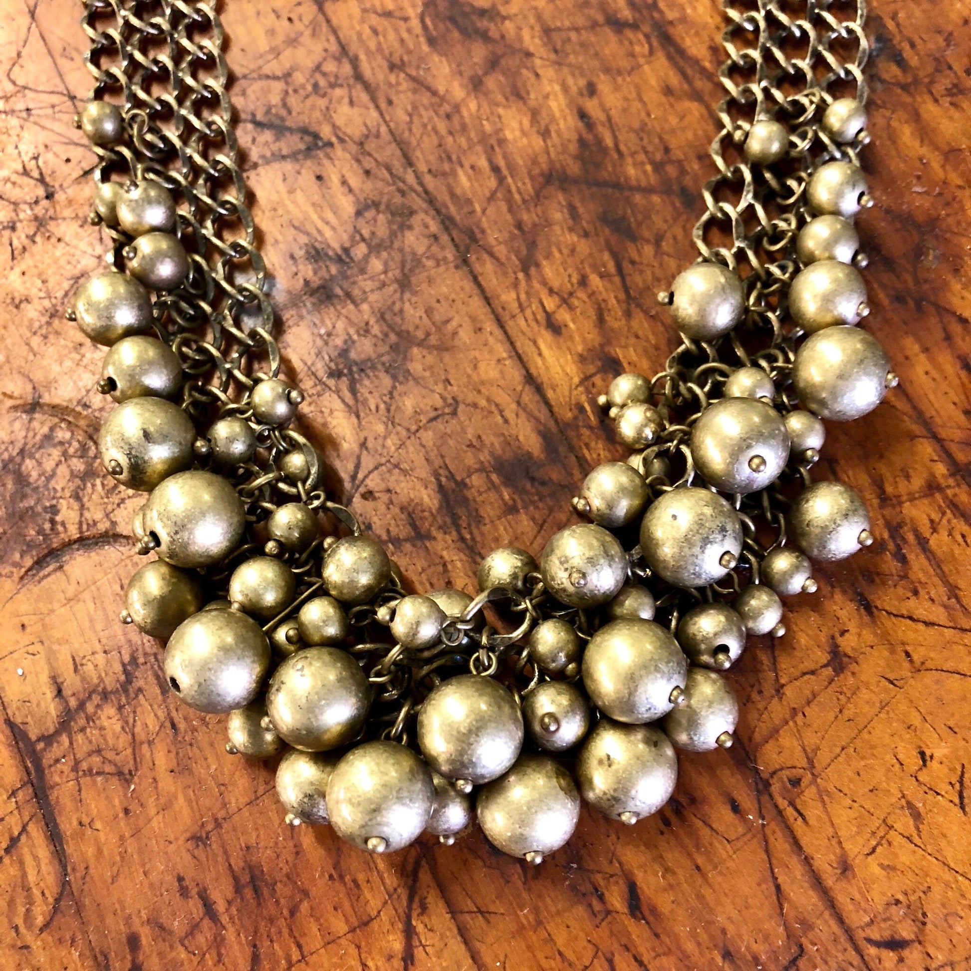 Vintage gold-toned brass ball bib statement necklace choker on wooden surface