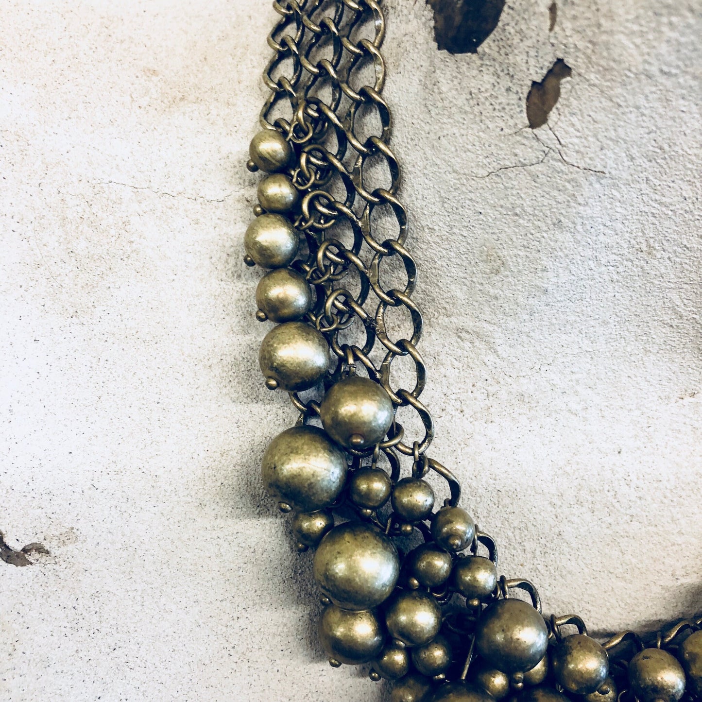 Vintage gold-toned brass ball choker necklace on textured surface