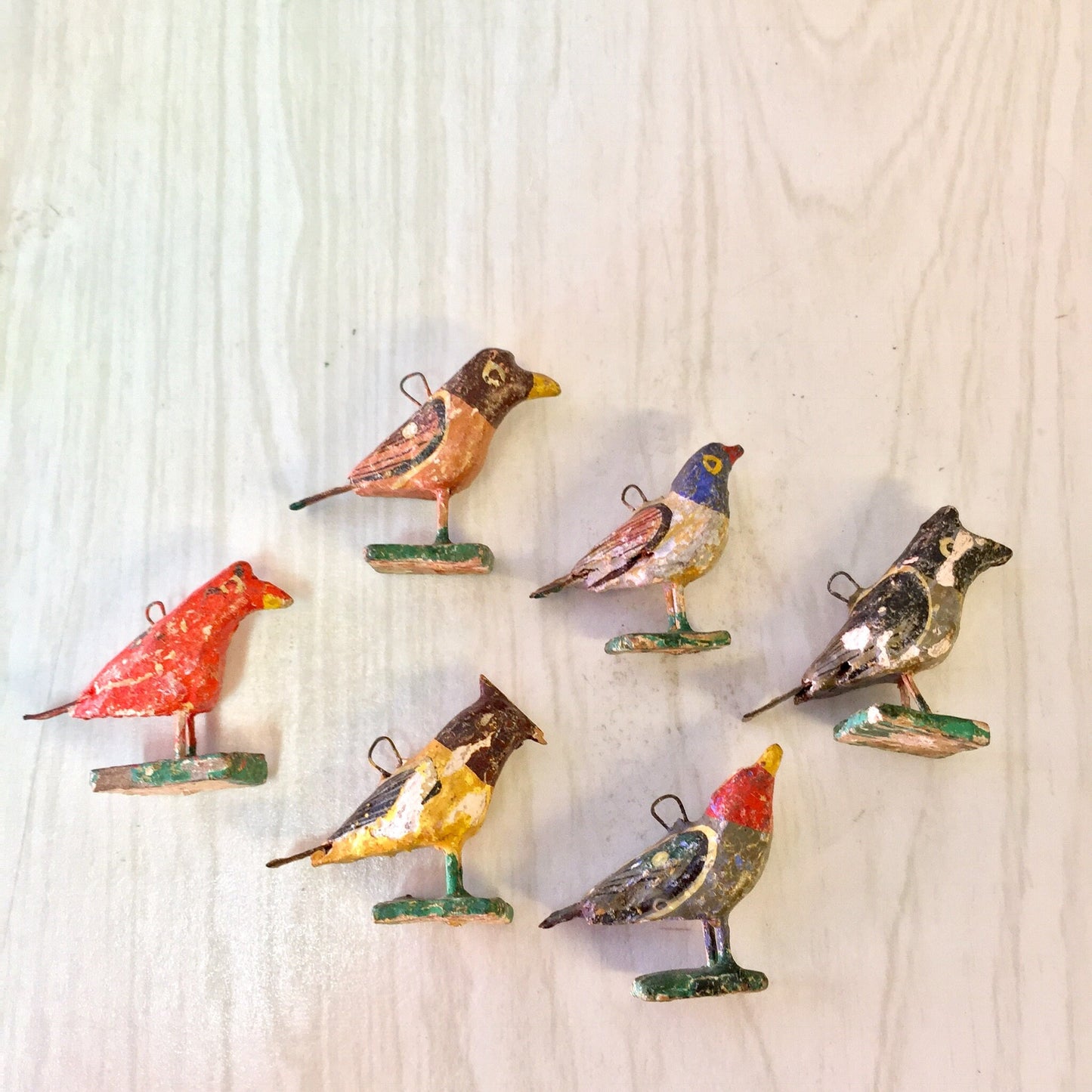 Colorful paper mache bird beads for jewelry making and crafting, including red, blue, yellow, and brown birds on stands, suitable for necklaces or bracelets.