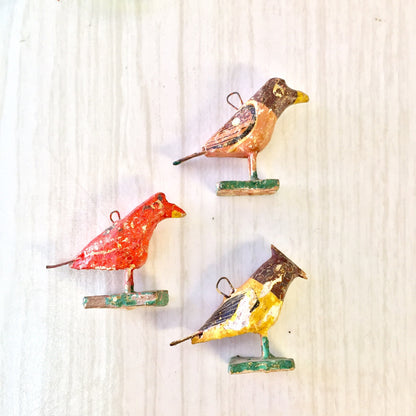 Colorful paper mache bird beads for jewelry making in red, yellow, and brown tones on a wooden surface, perfect for arts and crafts projects like necklaces or bracelets.