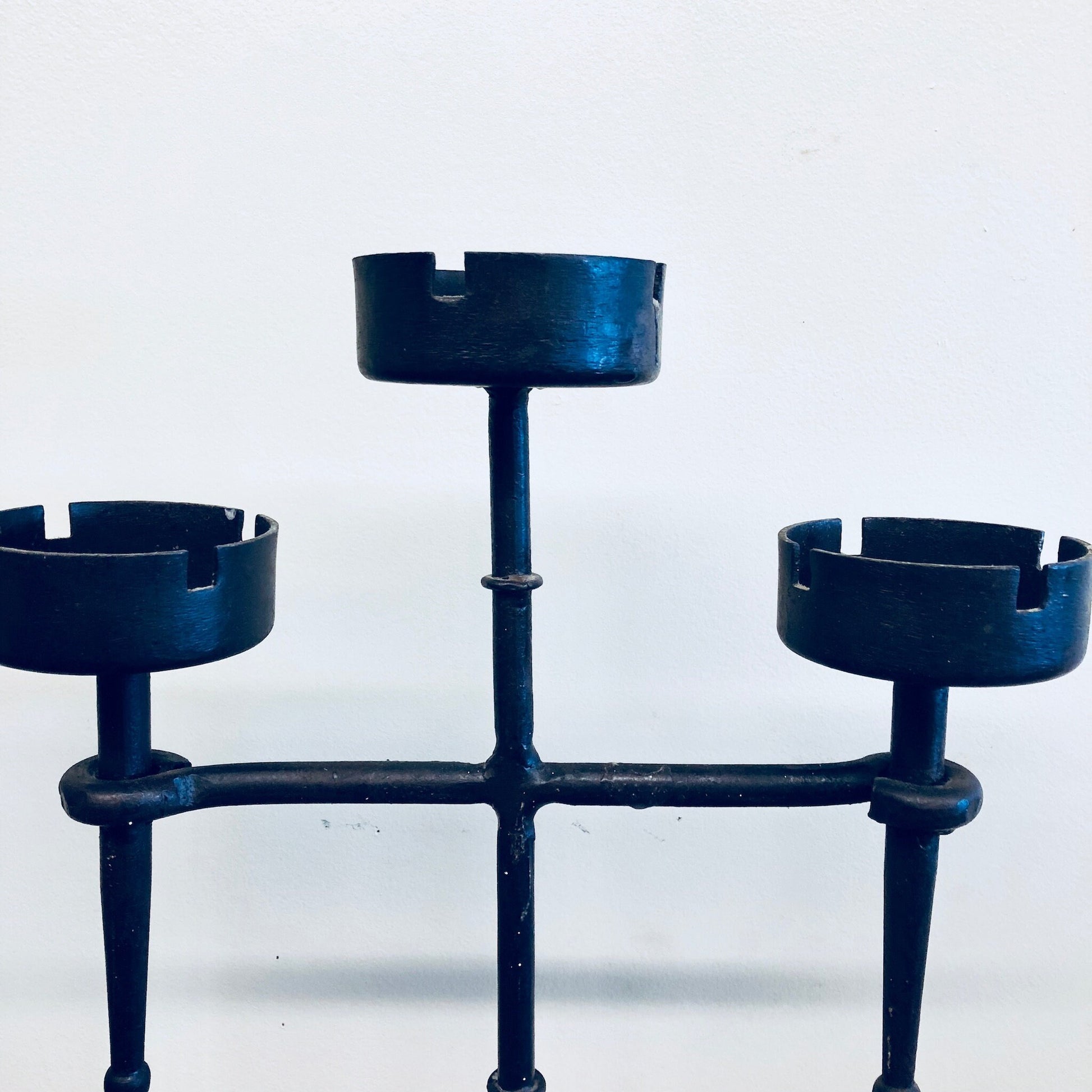 Vintage wrought iron candle holder with three candlesticks, rustic navy blue finish, suitable for use as a centerpiece, mantelpiece decor or ashtray.
