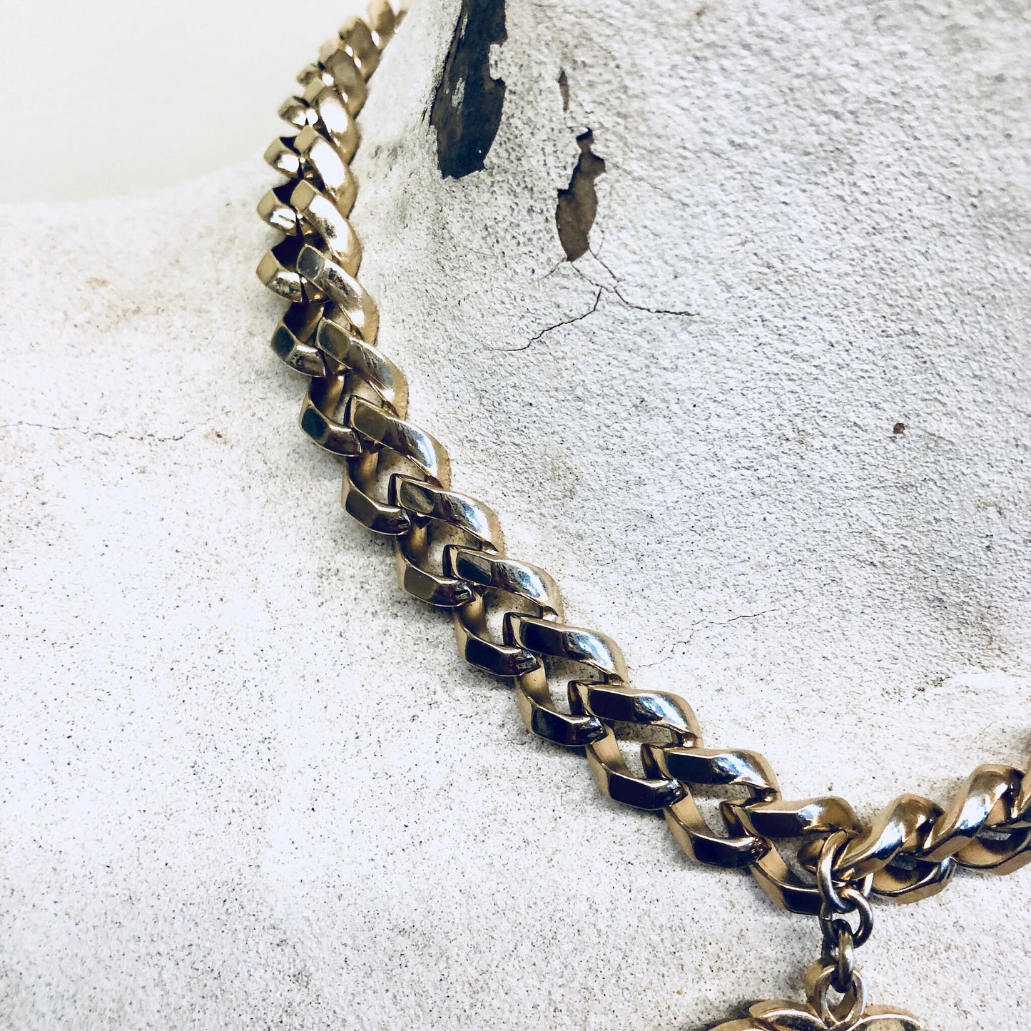 Vintage gold-toned thick chain necklace with navy blue enamel pendant by Monet jewelry, shown on cracked concrete surface.