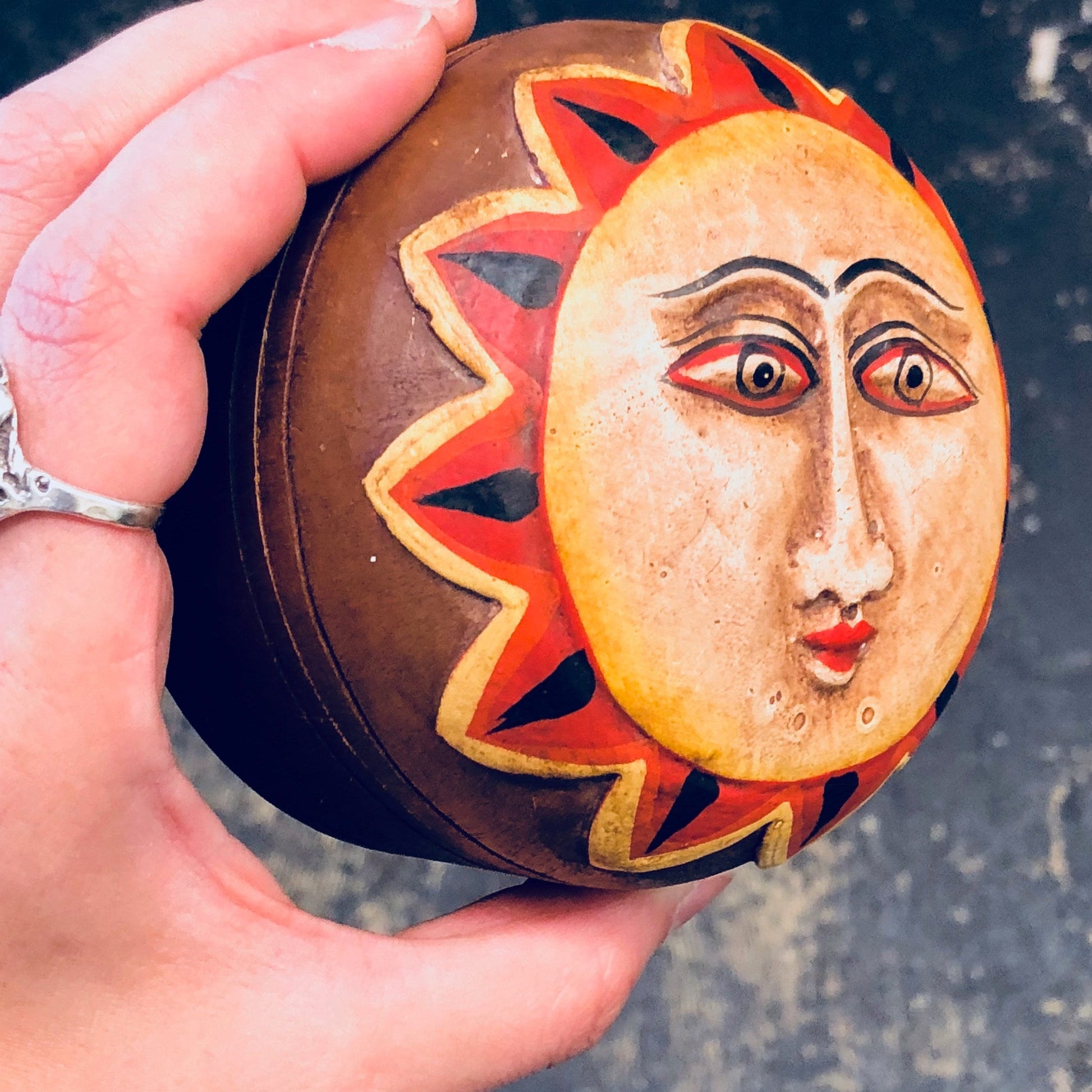 Vintage hand-carved wooden box with a decorative sun face design in red, orange, and yellow colors, used as a jewelry box or lidded container for home decor.