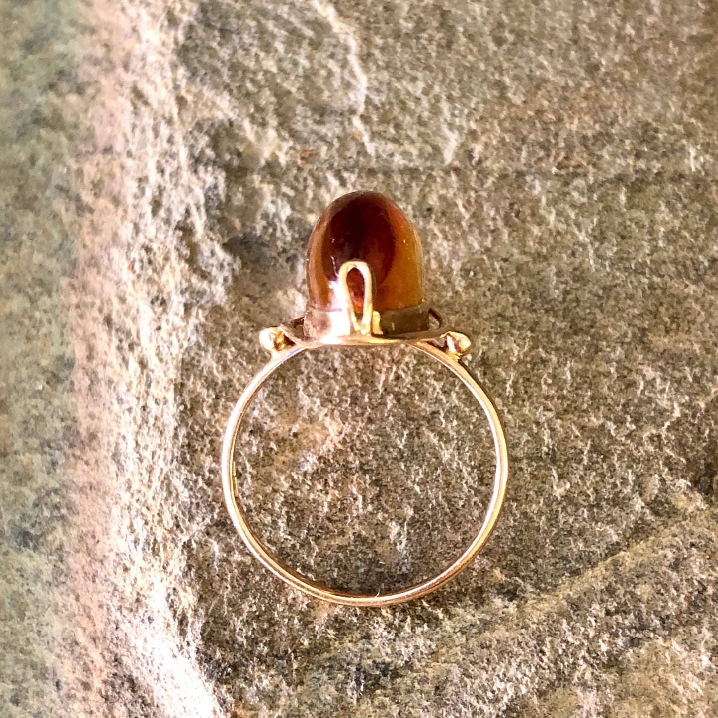 Vintage 10K yellow gold ring with amber stone, close-up view on textured gray background