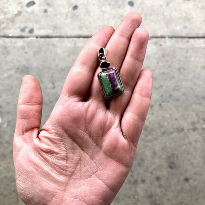 Vintage sterling silver pendant with green and purple natural stone, possibly a red garnet, held in an open hand