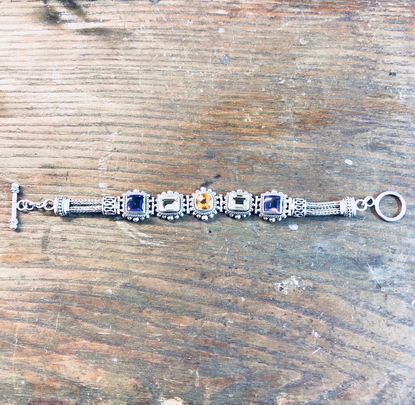 Vintage Sterling Silver Suarti BA Gemstone Bracelet with Amethyst, Peridot and Citrine Stones on Weathered Wooden Surface