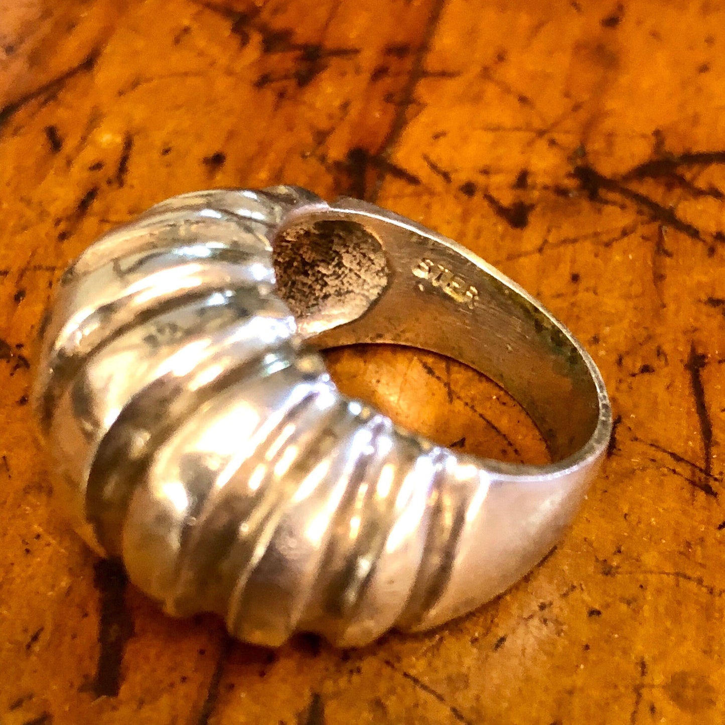 Vintage sterling silver statement ring with ridged design on rustic wooden surface