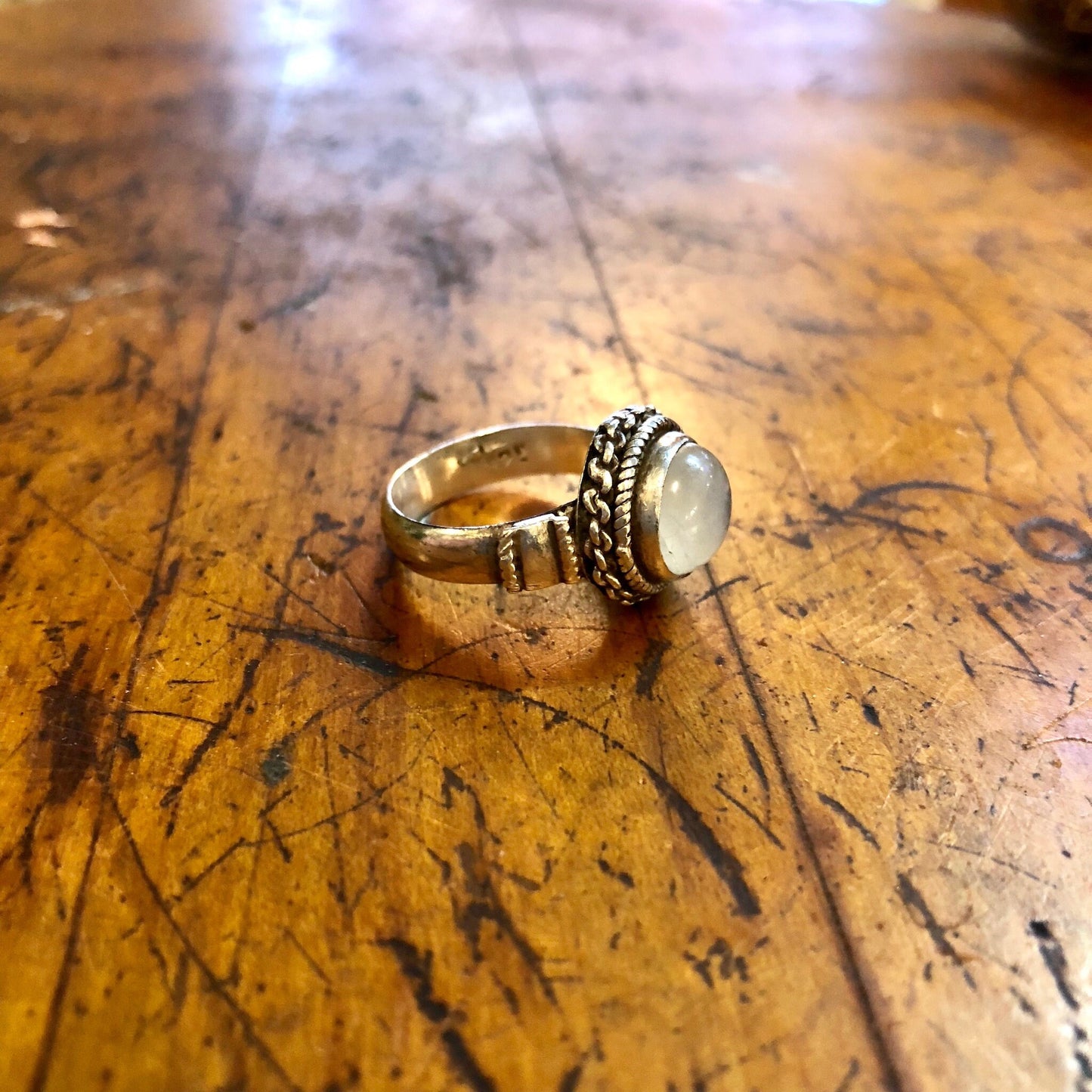 Vintage sterling silver moonstone ring with iridescent white stone on weathered wooden surface