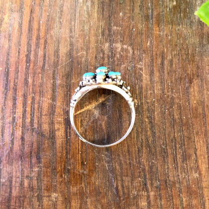 Vintage sterling silver ring with turquoise beads on weathered wooden surface