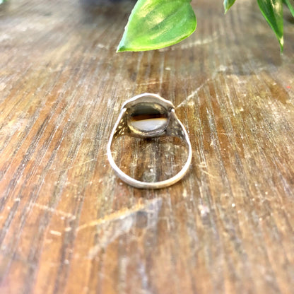 Vintage sterling silver ring with striped brown agate stone on rustic wooden surface with green leaves