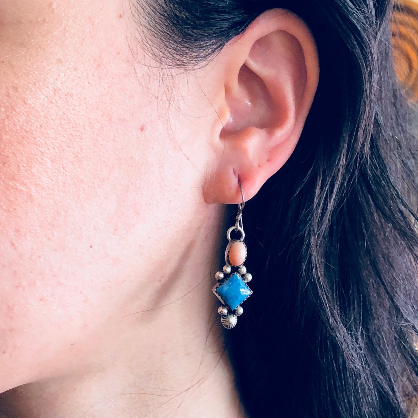 Blue and pink beaded dangle earrings worn on a woman's ear