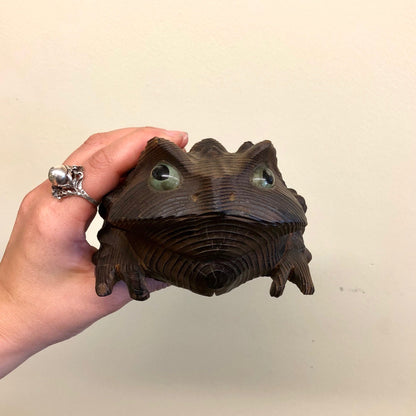 Wooden hand-carved frog sculpture with intricate details and realistic texture, perfect as a vintage home decor accent piece or mantlepiece display in brown, black and green tones.