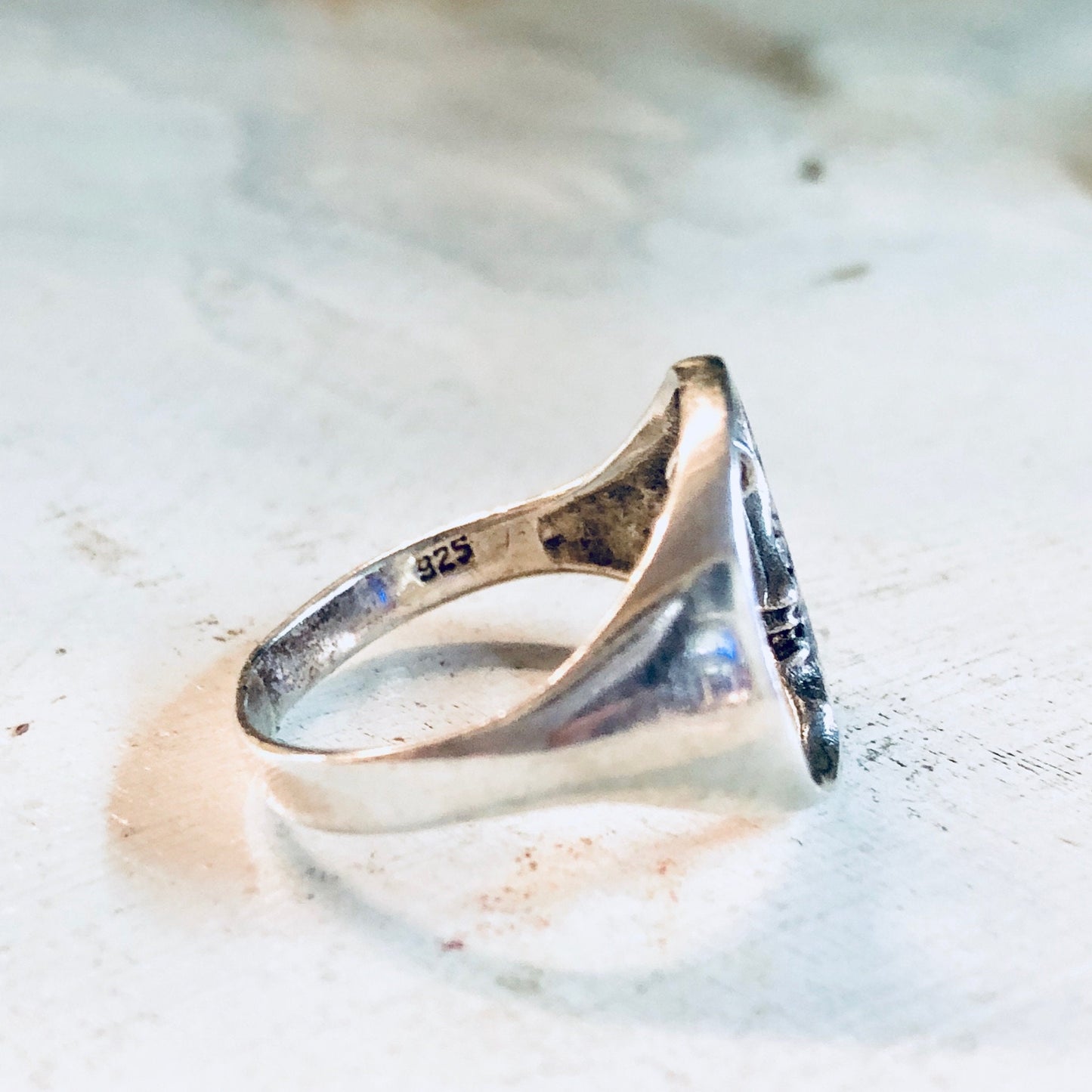 Vintage sterling silver moon and star cutout bohemian style promise ring on textured stone surface.