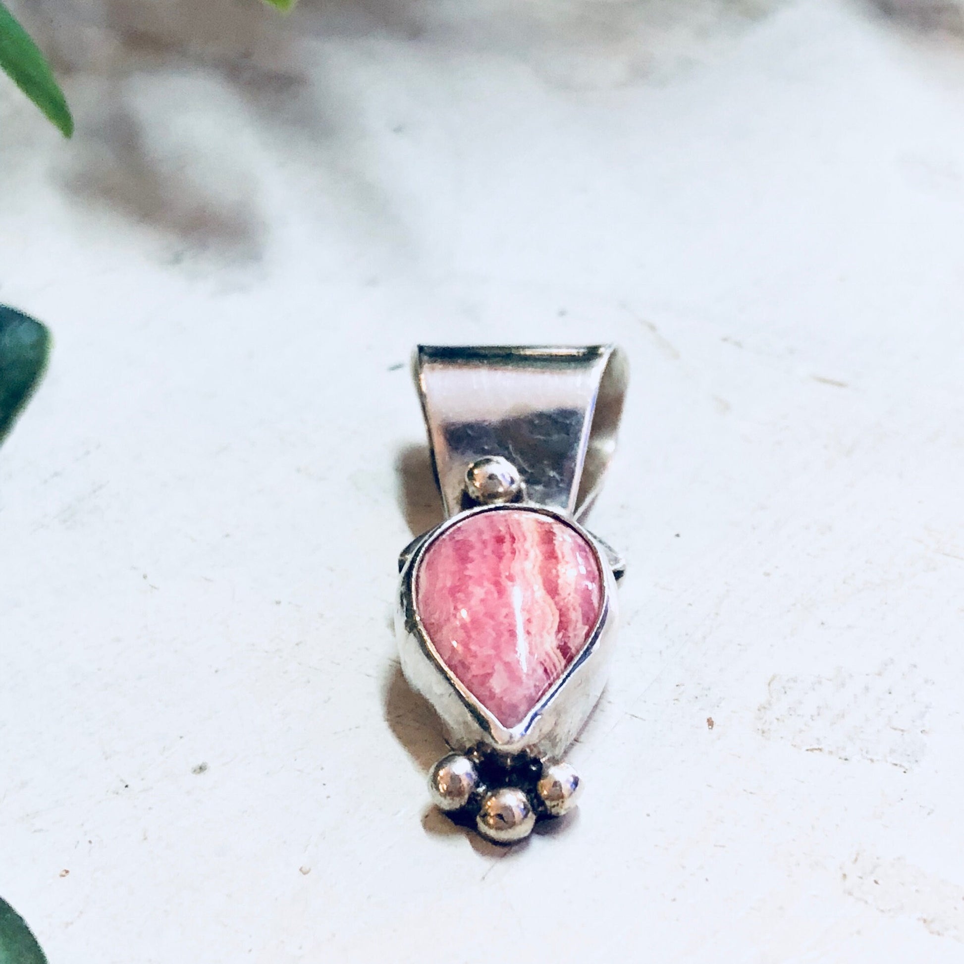 Vintage sterling silver pendant with pink rhodochrosite gemstone, pink and white color palette, unique artistic design, antique jewelry style.