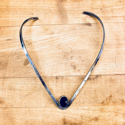 Vintage sterling silver choker necklace with black onyx stone forming a V-shape collar on a wooden background