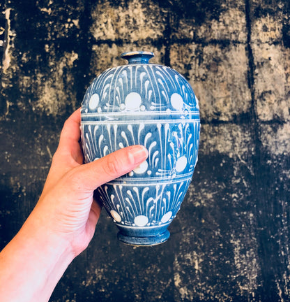 Hand holding a decorative blue and white ceramic vase against a grungy textured background
