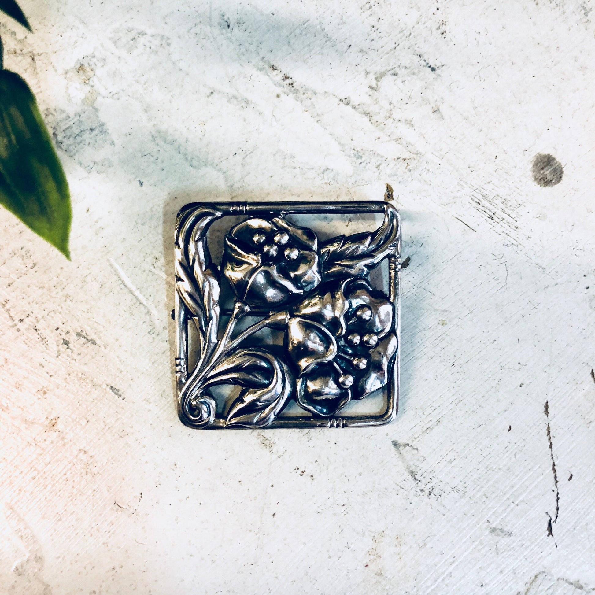 Vintage Dancraft sterling silver floral brooch pin with blooming flower design from the 1940s, photographed on a light textured background.