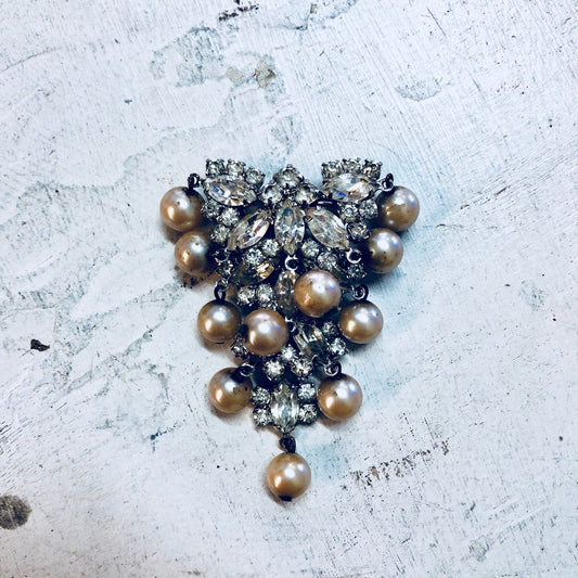 Vintage brooch with rhinestones and faux pearls in an art deco style on a weathered background