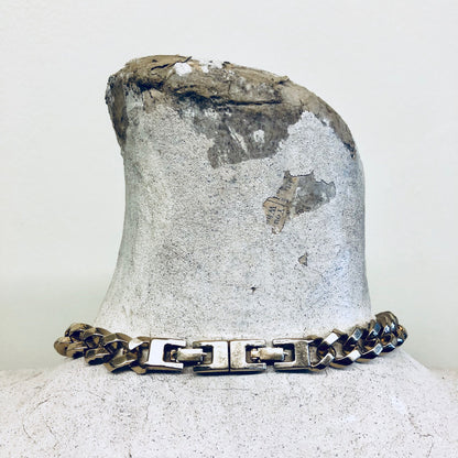 Vintage Monet gold-toned thick chain necklace with blue and white enamel pendant, displayed on weathered concrete surface.