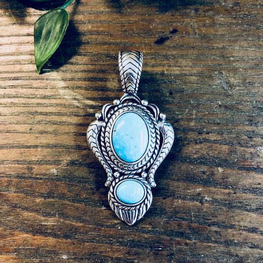 Vintage sterling silver and turquoise pendant in southwestern style on a wooden surface with a leaf accessory, statement vintage jewelry necklace