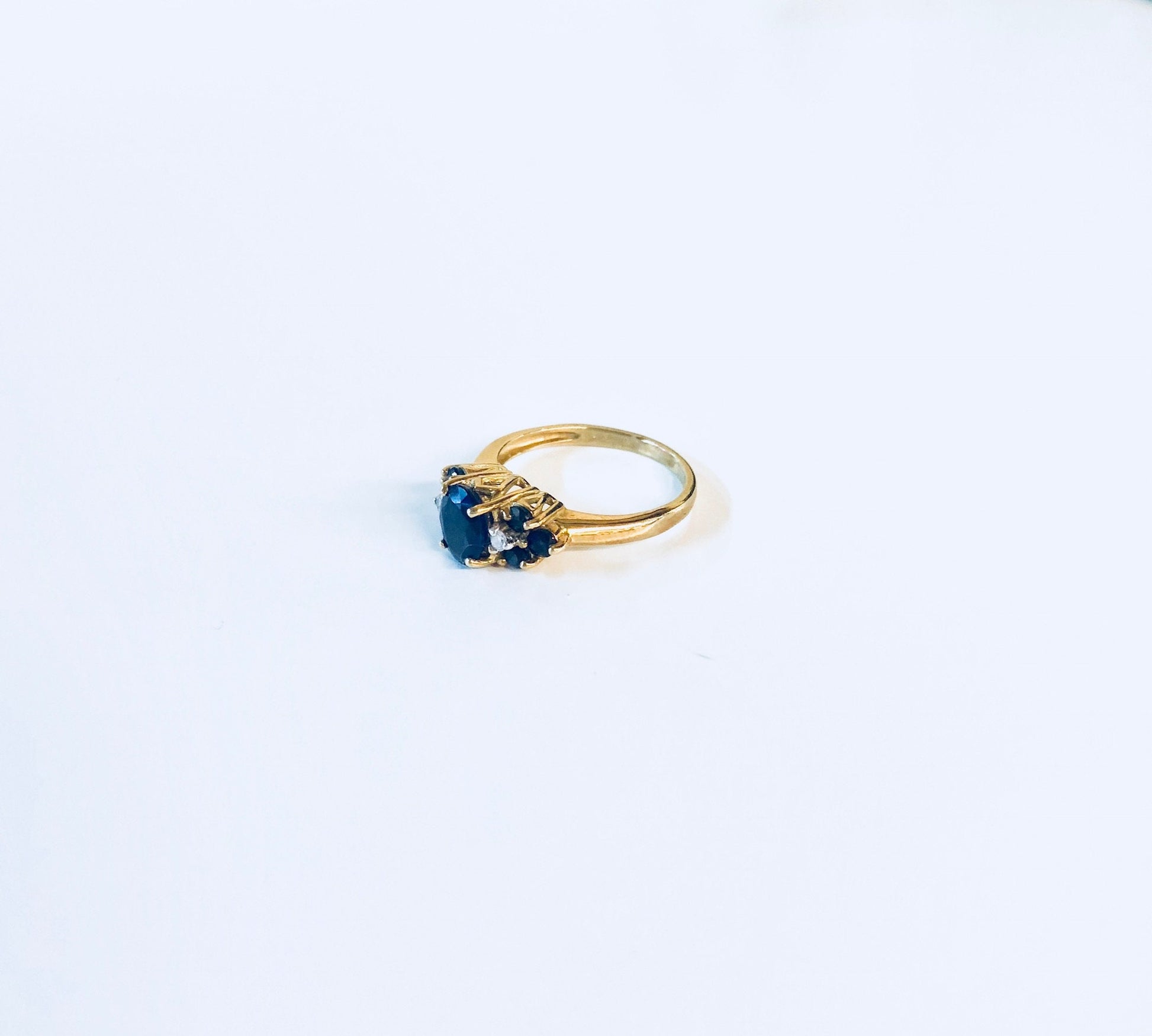 Vintage 14K yellow gold sapphire ring with three blue sapphire stones set in a row on a simple gold band, perfect for an engagement ring, wedding band, or September birthstone jewelry.
