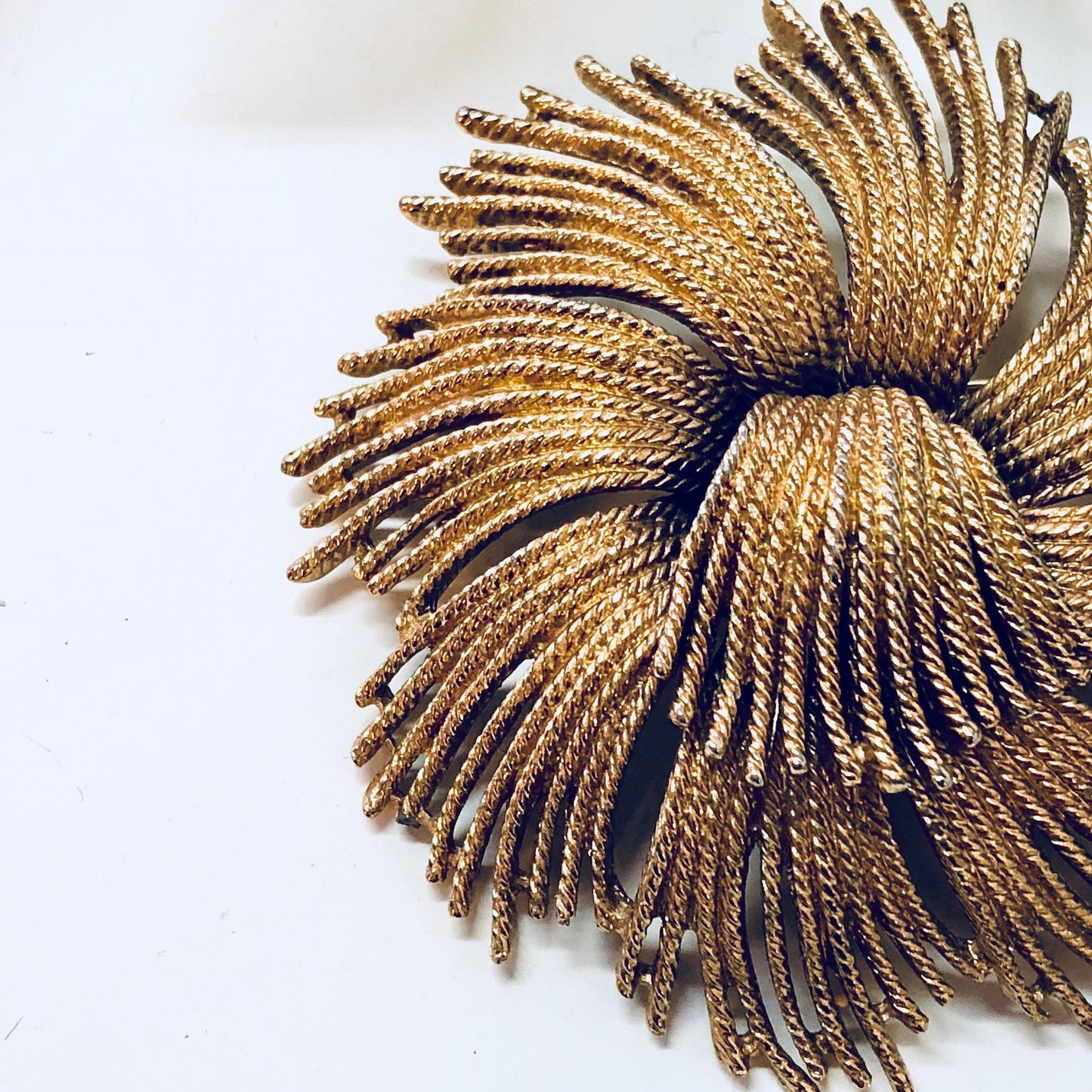 Vintage gold-toned Monet brooch with swirling spiral design, a unique statement jewelry piece from a bygone era.