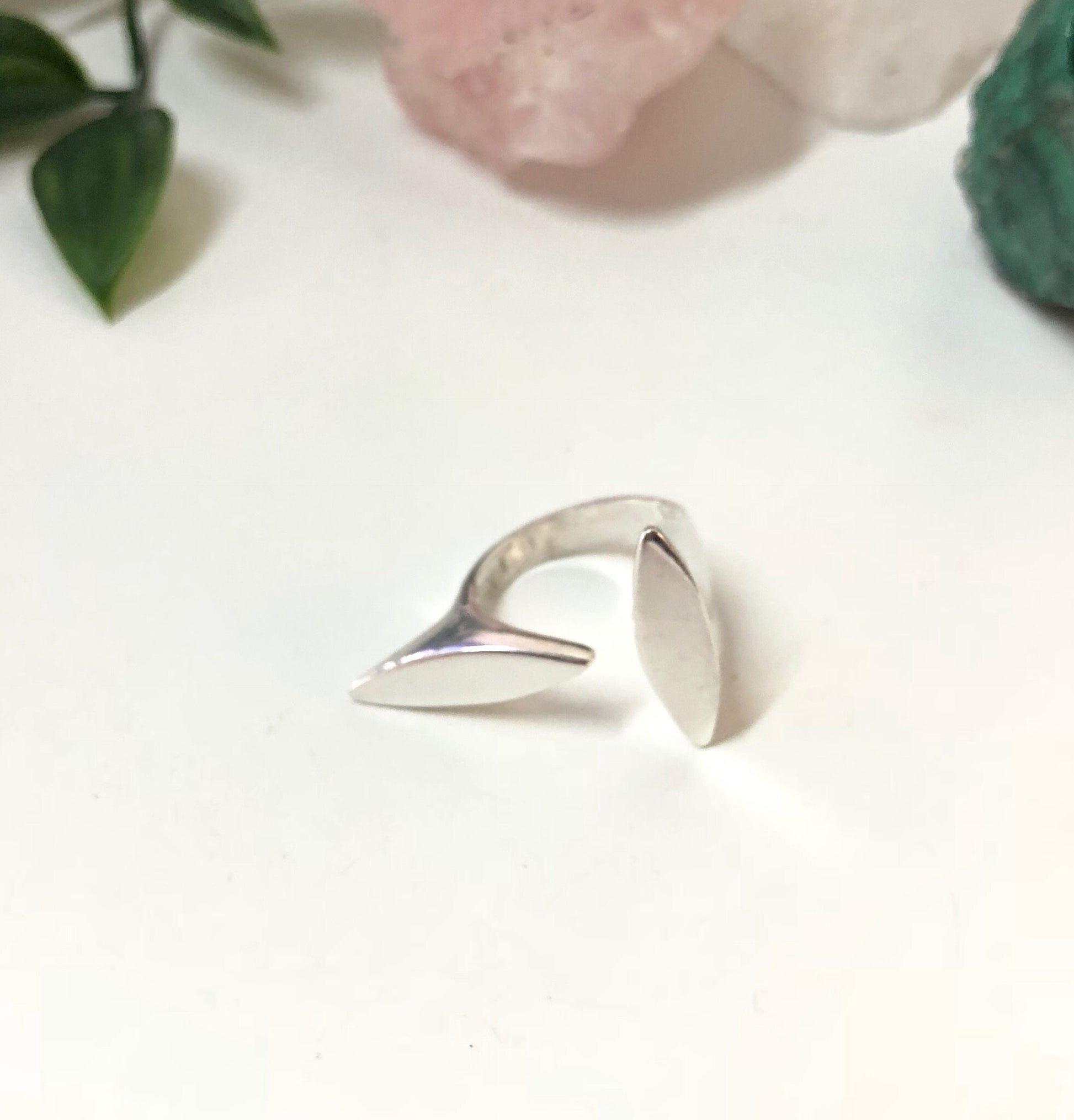 Vintage abstract sterling silver minimalist ring on white background with pink rose petals and leaves