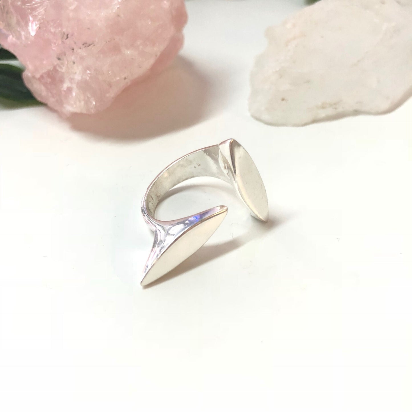 Vintage abstract sterling silver minimalist ring with geometric design and pink stone or glass accent, displayed with rose quartz crystals on white background.