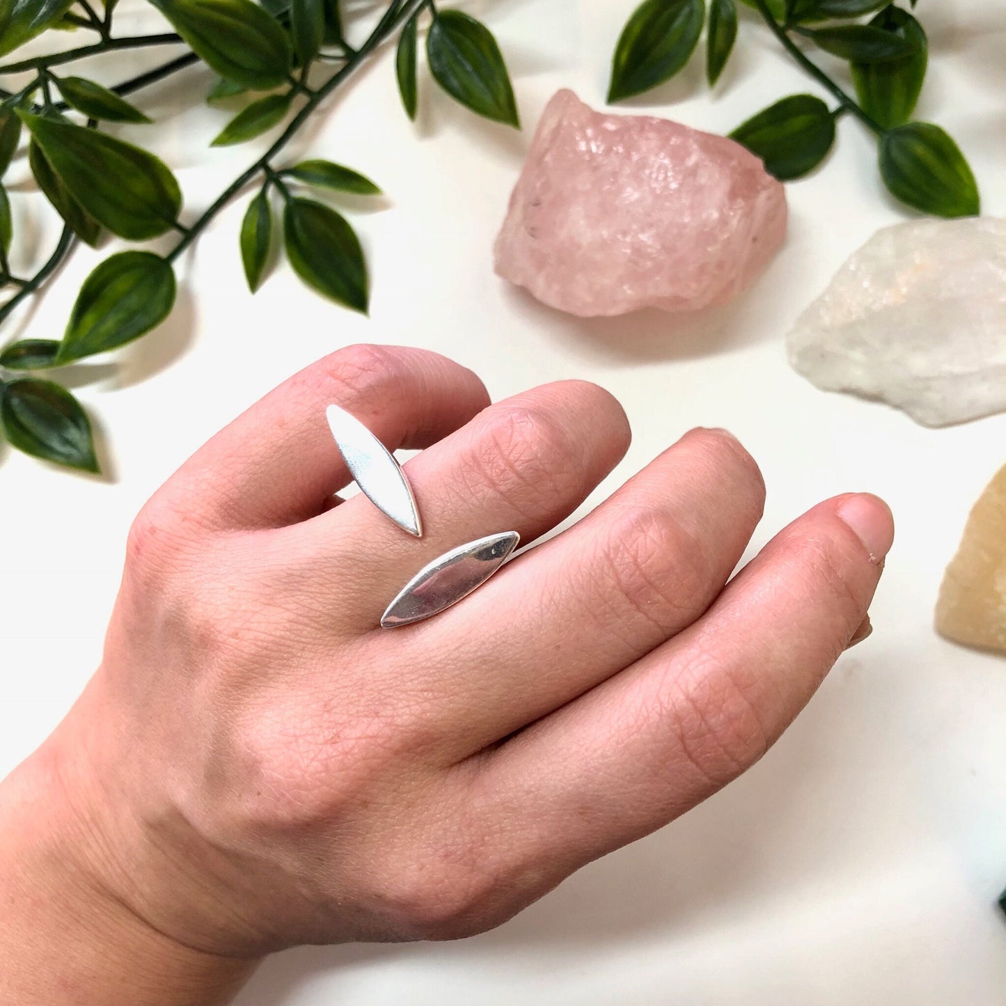 Vintage abstract sterling silver minimalist ring on hand with rose quartz crystal and green leaves