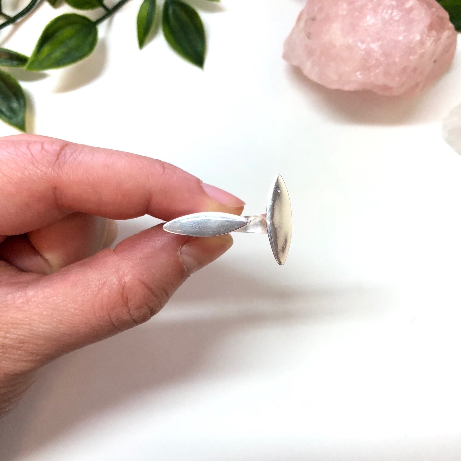 Vintage abstract sterling silver minimalist ring held between fingers with rose quartz crystal in background