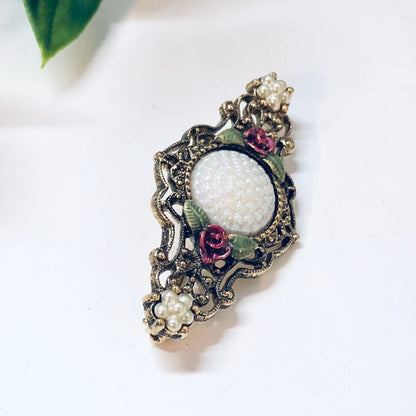 Vintage gold-toned floral brooch pin with faux pearl and colorful enamel accents, intricate metalwork design, costume jewelry accessory