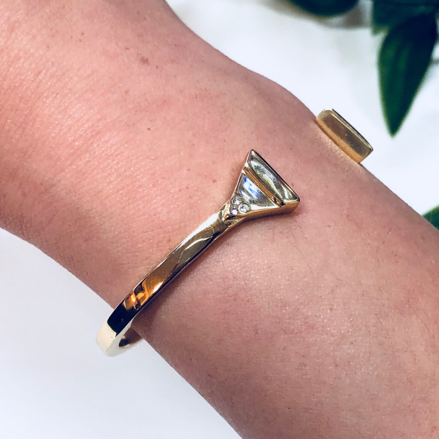 Gold toned triangle-shaped cuff bracelet on wrist