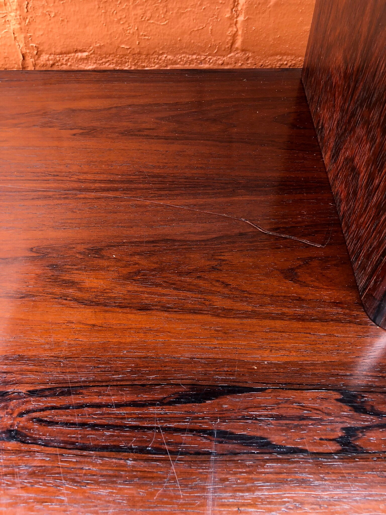 Mid-century modern teak credenza with rich, warm wood grain and brick wall backdrop