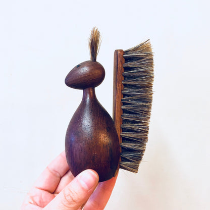 Vintage wooden animal-shaped brush with bristles held in hand, rustic brown decor piece