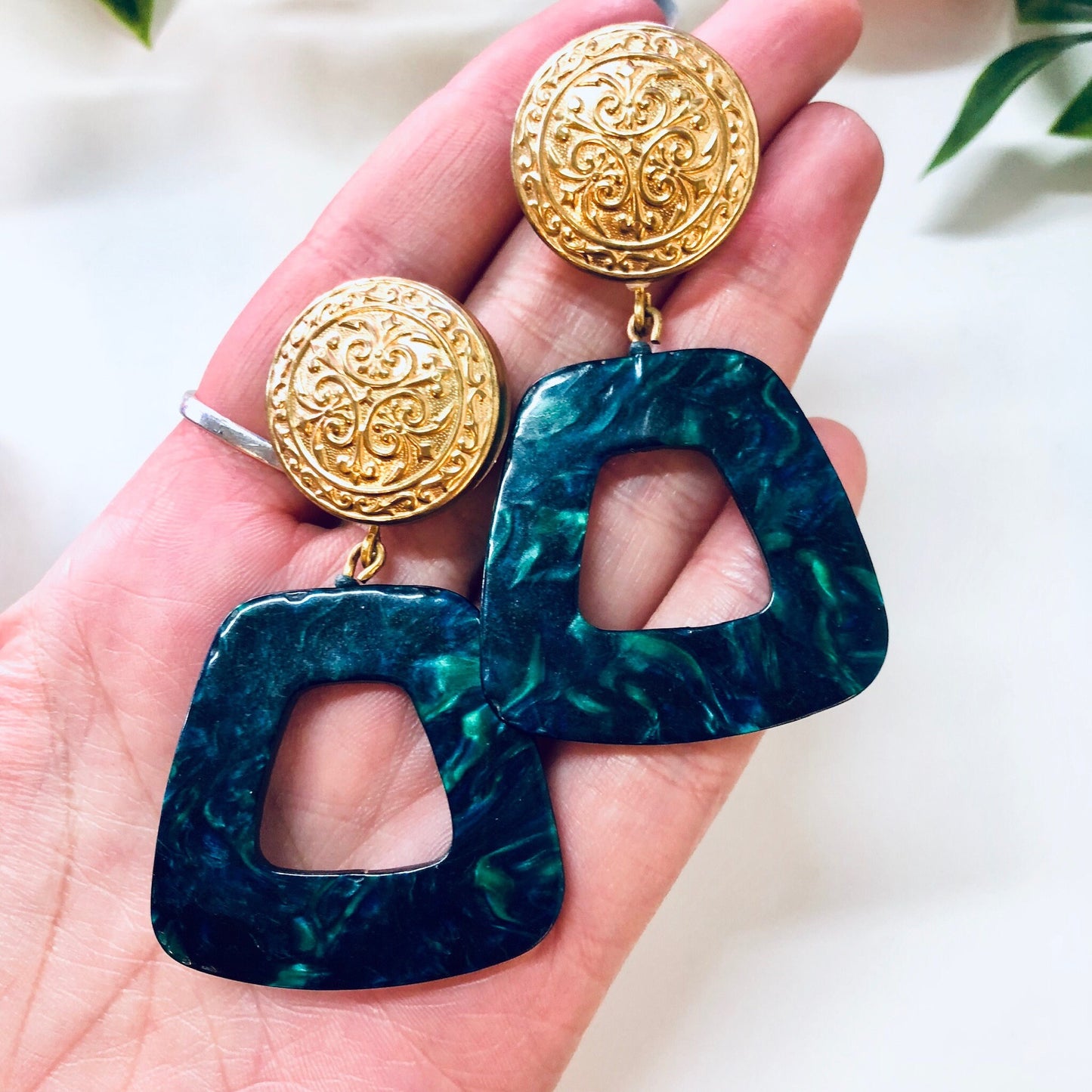 Vintage gold filigree and teal marble acrylic dangle earrings held in palm of hand