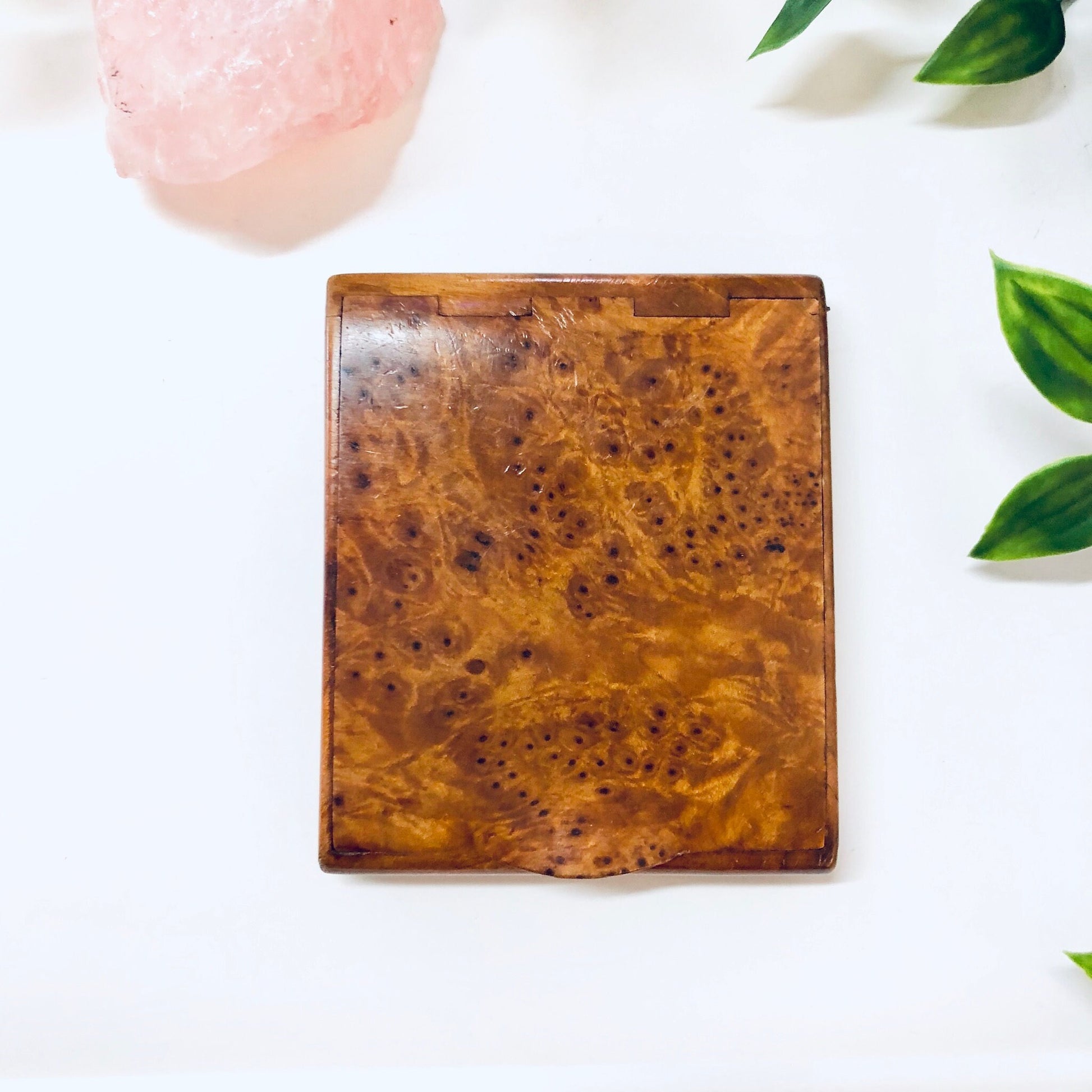 Vintage wooden hinged box with a light brown burl wood grain pattern, suitable for use as a cigarette case, business card holder, or small container. Decorative leaves surround the closed box.