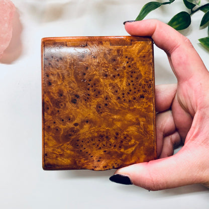 Vintage wooden hinged box held in hand, showing textured light brown burl wood grain pattern. Small case suitable for cigarettes, business cards or small items.