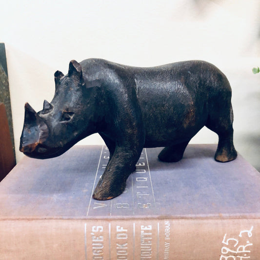 Vintage wood carving of a rhinoceros statue with intricate details and a dark, natural wood finish, perfect as a unique animal-themed decor piece for an animal lover.