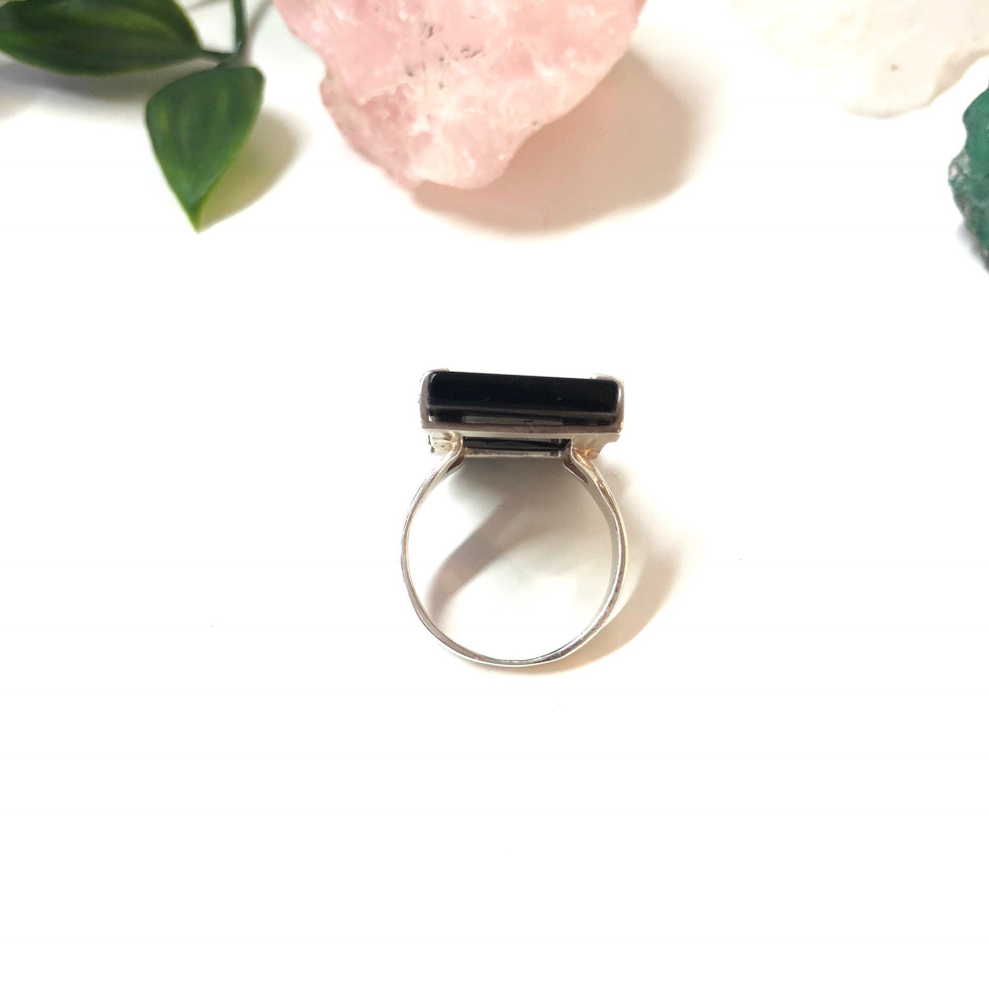 Vintage sterling silver ring with rectangular black onyx stone, minimalist design, shown with pink crystal and greenery backdrop