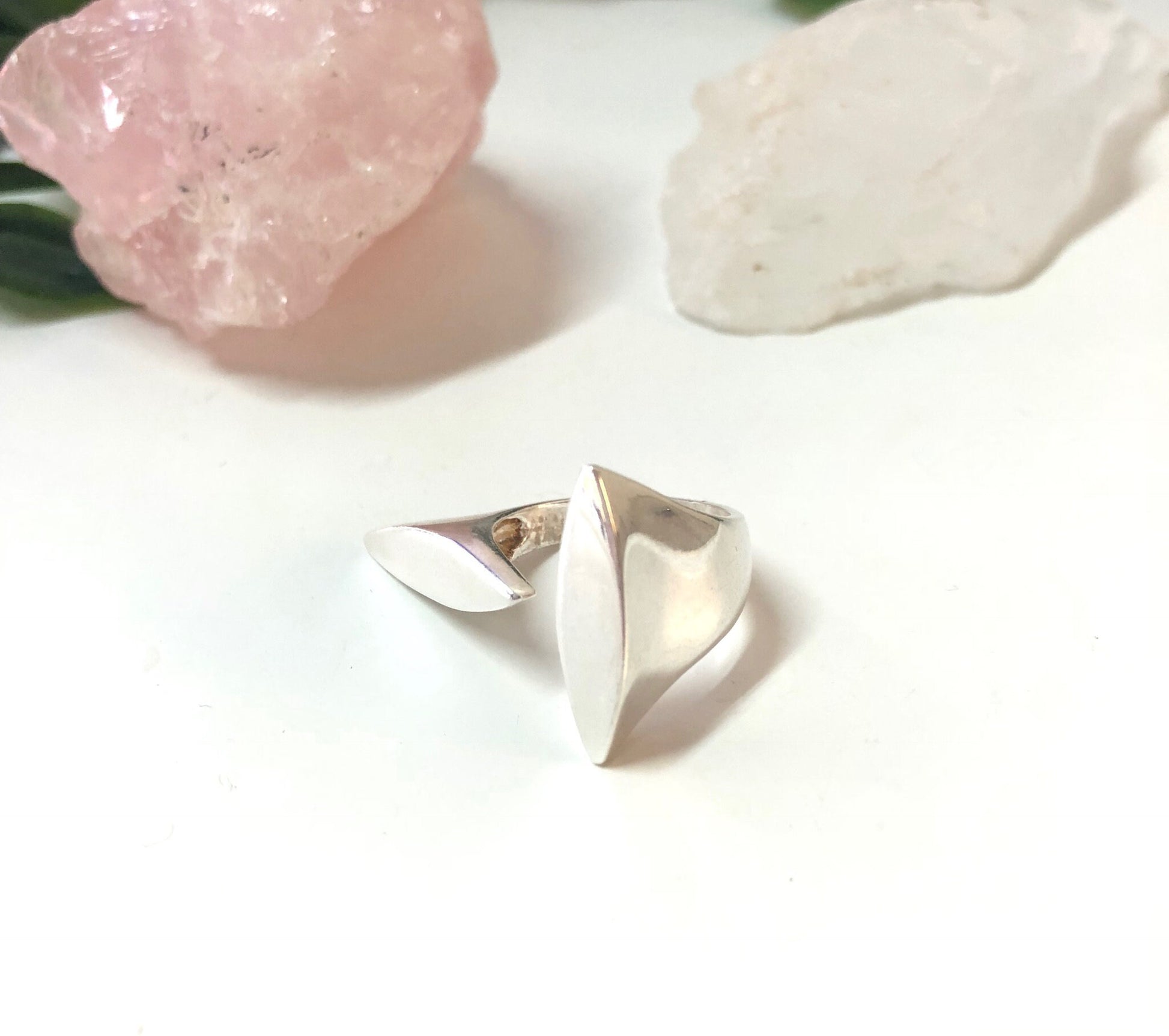 Vintage abstract sterling silver minimalist ring displayed on white surface with rose quartz crystal in background