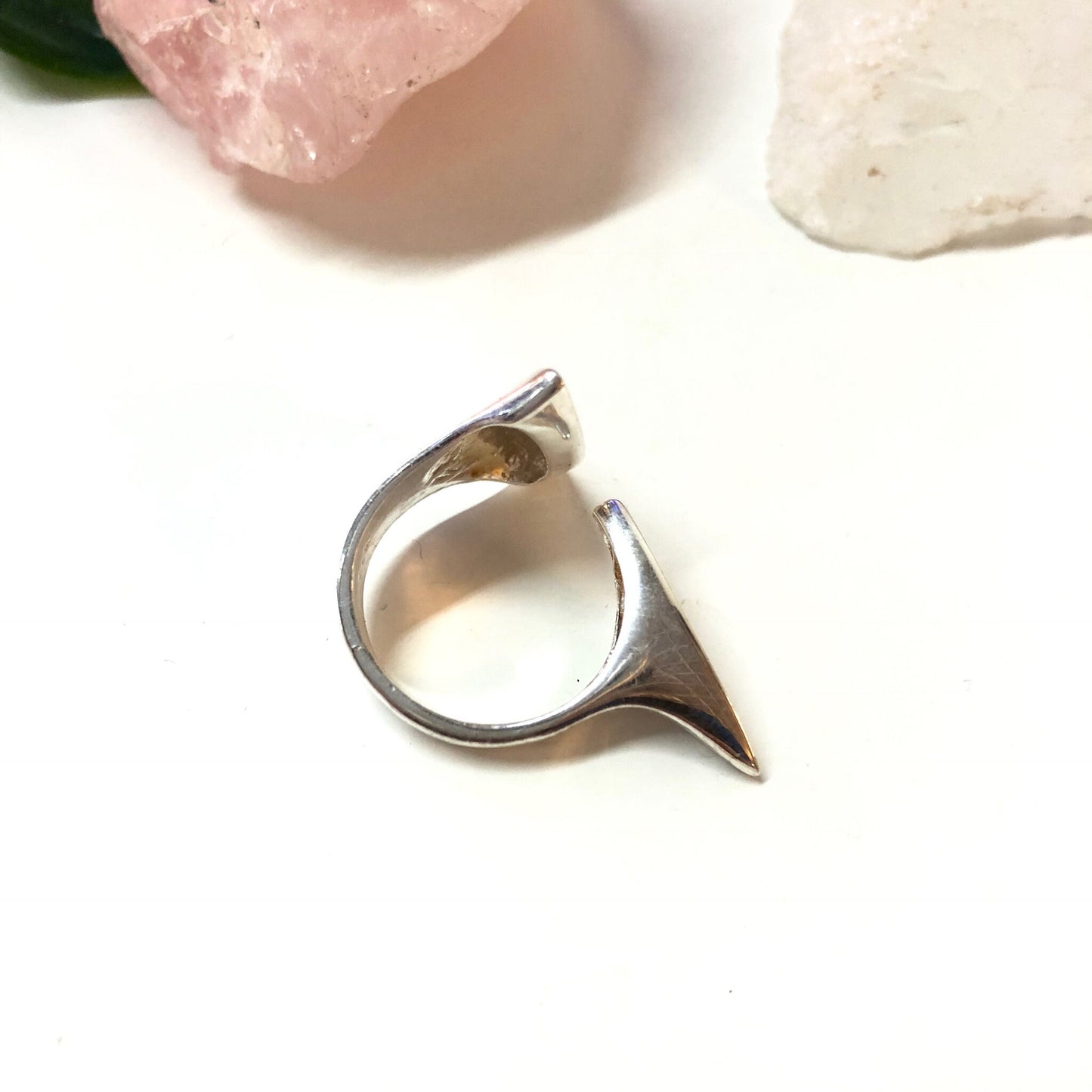 Vintage abstract sterling silver minimalist ring with curved geometric shape on white background with rose quartz crystal