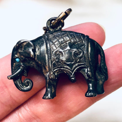 Vintage sterling silver elephant watch fob pendant with engraved details and ball, held in palm of hand