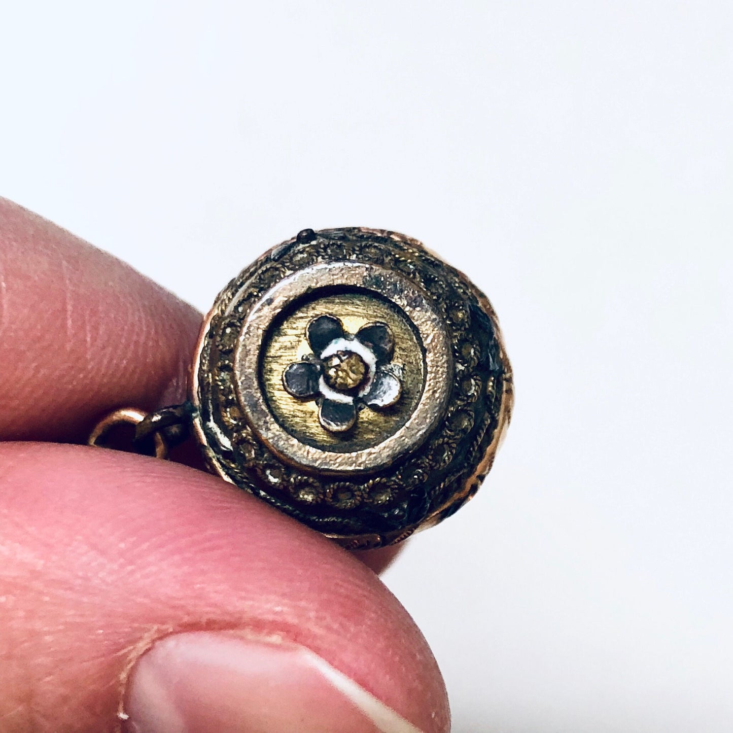 Antique sterling silver watch fob featuring an engraved elephant design, attached to a textured metal ball. The fob is held in a person's fingers to show detail against a white background.