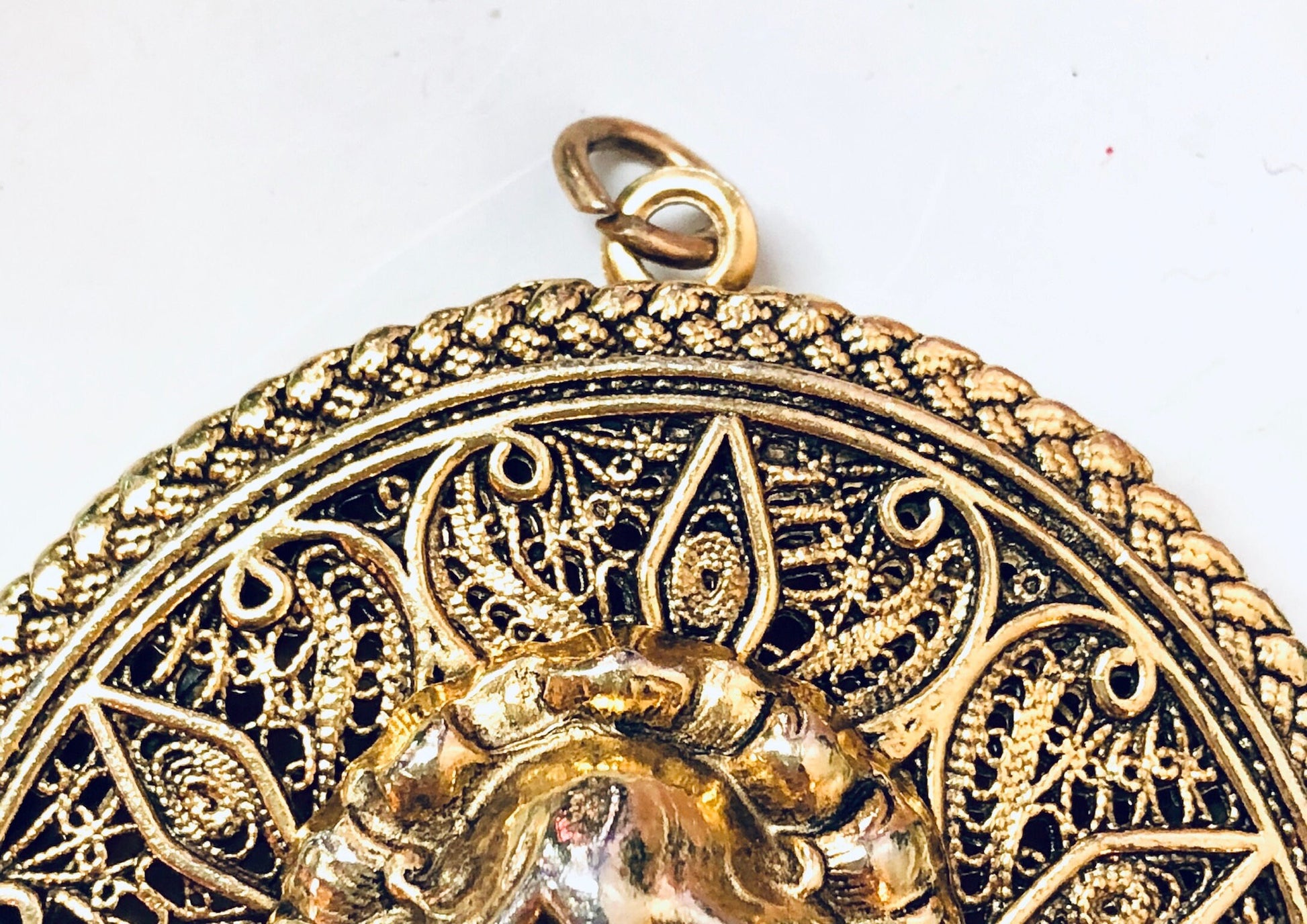 Ornate vintage gold-toned locket pendant featuring intricate filigree design and floral motif