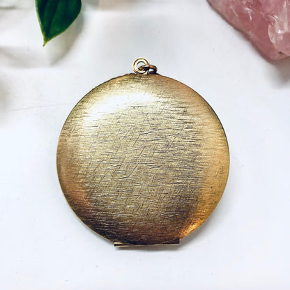 Vintage gold toned round locket pendant necklace with brushed metallic finish