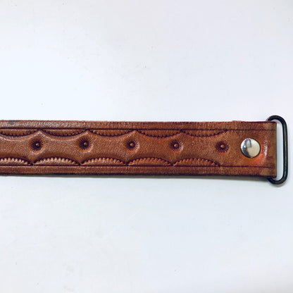 Vintage brown leather cowboy belt with embossed geometric pattern and silver hook buckle, skinny style reminiscent of the Southwest