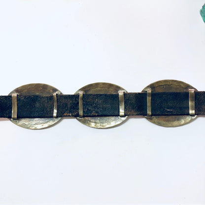 Vintage skinny concho belt made of brown leather with three brass conchos connected by blue suede, displayed on a white background.