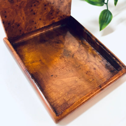 Vintage wooden hinged box with aged patina, serving as a cigarette case, business card holder or small container, displayed open with a plant sprig beside it.
