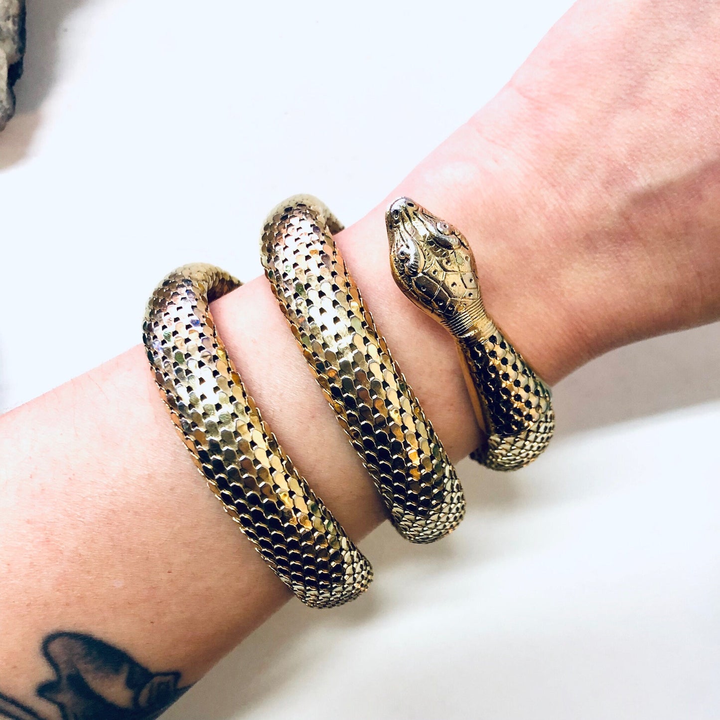 Gold-toned vintage snake bracelet with coiled mesh design, styled on wrist with tattoo